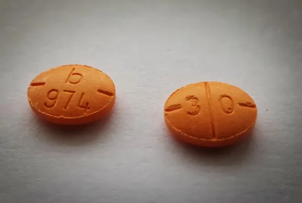 Two orange Adderall tablets on a table
