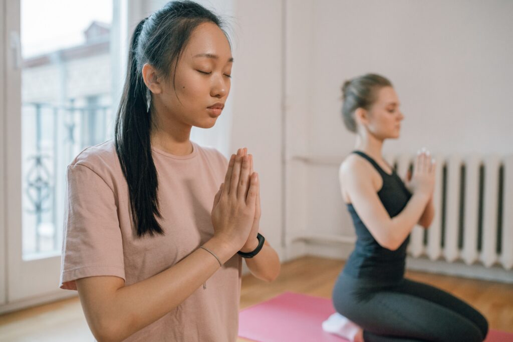 Two women practicing yoga and meditation indoors